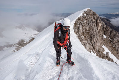 High angle view of man climbing snow covered mountain