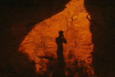 Silhouette of person against red cave entrance at sunset in desert