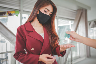 Young woman holding camera while standing at home