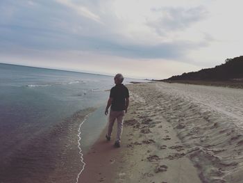 Rear view of people walking on beach