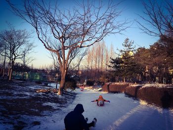 People on snow covered landscape against sky