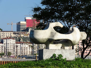 Statue against trees and buildings in city