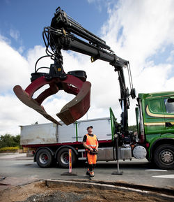 Construction worker standing by construction vehicle