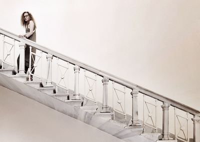 Low angle view of woman standing on staircase against clear sky