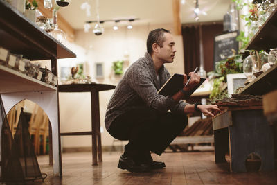 Worker examining plants in garden center