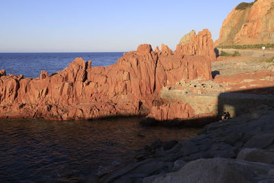 Rock formations by sea against clear sky