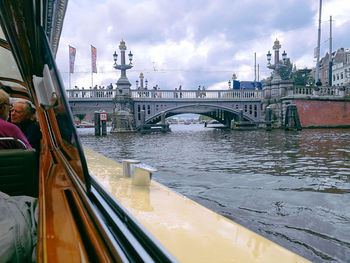 Bridge over river in city against sky