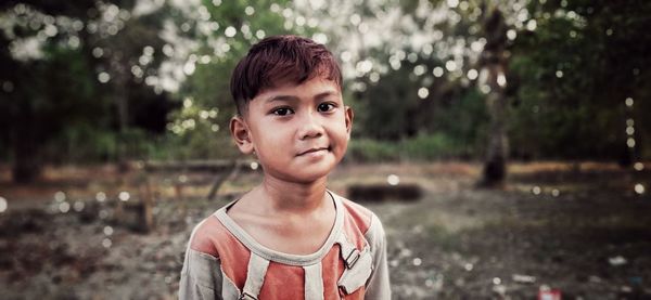 Portrait of boy standing against trees