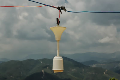 Close-up of light bulb hanging against sky