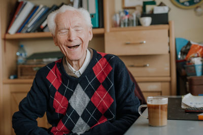 Smiling senior man with coffee cup on table at home