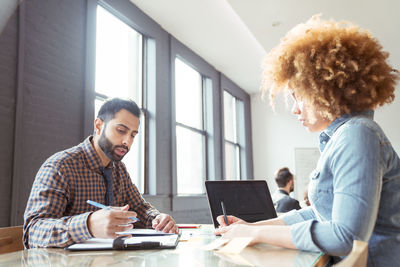 Business people working while sitting at table in office