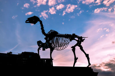 Low angle view of silhouette skeleton against sky