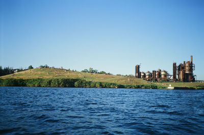 Scenic view of lake by buildings against clear blue sky