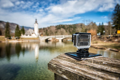 Cross on river by building against sky