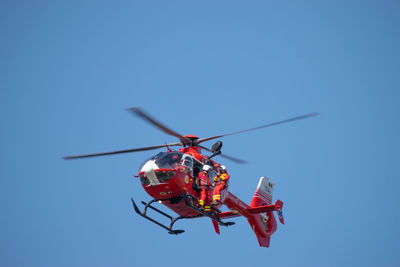 Low angle view of helicopter flying against clear blue sky