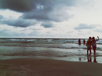 Men standing on beach against sky