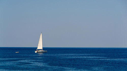 Sailboat sailing on sea against clear sky