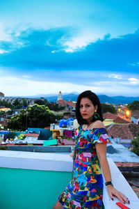 Portrait of woman standing by swimming pool against sky