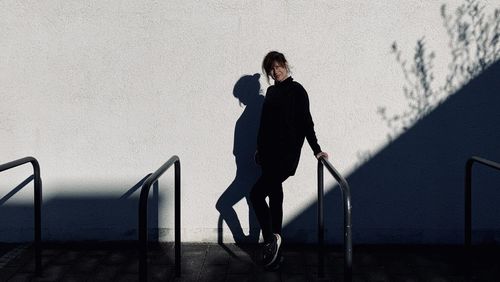 Woman standing by railing against wall