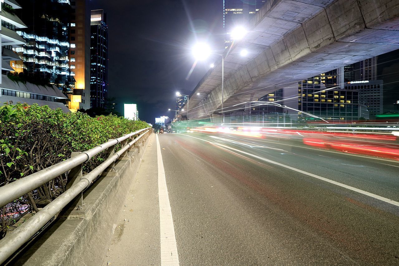 LIGHT TRAILS ON STREET IN CITY AT NIGHT