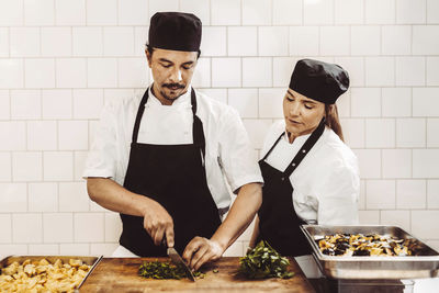 Friends standing on cutting board in kitchen