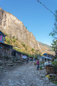 People on rocky mountain against clear blue sky