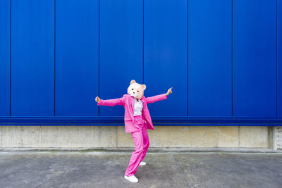 Full length of girl standing against pink wall