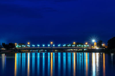 Illuminated bridge over river against sky at night