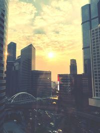 Modern buildings in city against sky during sunset