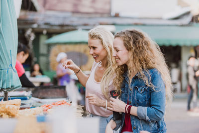 Women buying food at street market stall