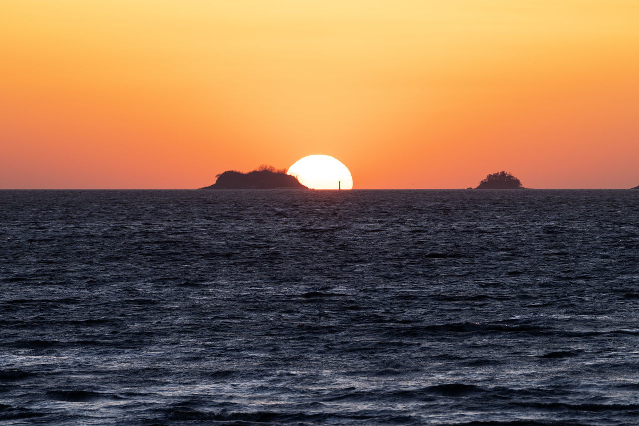 sunset, sky, sea, water, horizon, beauty in nature, scenics - nature, sun, nature, ocean, orange color, tranquility, environment, tranquil scene, horizon over water, dramatic sky, land, no people, idyllic, sunlight, travel, travel destinations, coast, landscape, outdoors, afterglow, silhouette, seascape, urban skyline, dusk, non-urban scene, tourism, romantic sky, motion, summer, wave, vacation, cloud, trip, atmospheric mood, transportation, shore, holiday, architecture