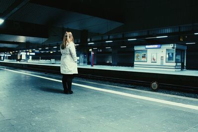 Woman standing on railroad station platform at night