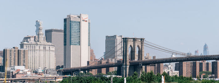 Bridge by buildings against clear sky