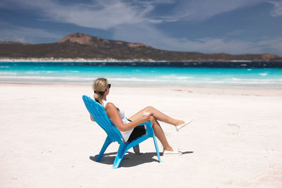 Rear view of woman standing at beach against sky