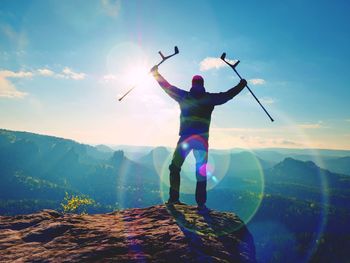 Rear view of person standing on mountain against sky