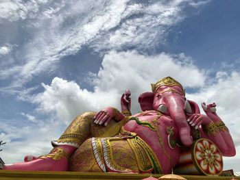 Low angle view of ganesha against cloudy sky