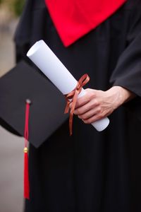 Midsection of male university student holding degree