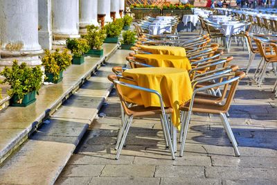 Empty chairs and tables at sidewalk cafe against building