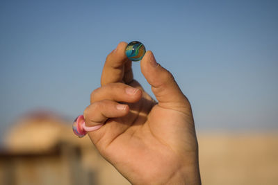 Close-up of man holding hands against sky