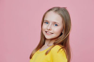 Portrait of young woman against pink background