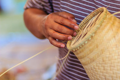 Midsection of man making wicker decoration