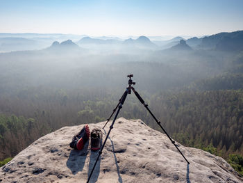 Modern professional travel tripod and black red sneakers on mountain summit. hiking and takes photos 