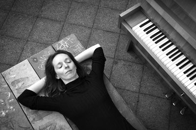 High angle view of woman sleeping by piano on table