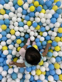 Directly above shot of baby girl sitting at ball pool