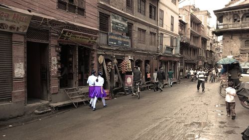 People walking on street amidst buildings in city