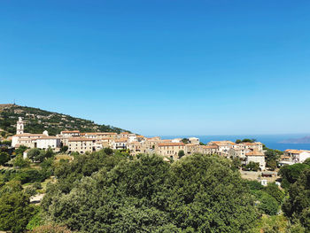 Buildings in city against clear blue sky