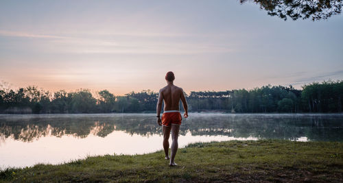 Rear view of man standing against lake
