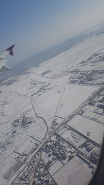 Close-up of airplane flying over landscape against sky