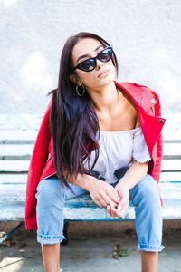 Portrait of young woman wearing sunglasses sitting outdoors