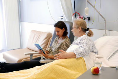 Grandmother and granddaughter using digital tablet in hospital ward